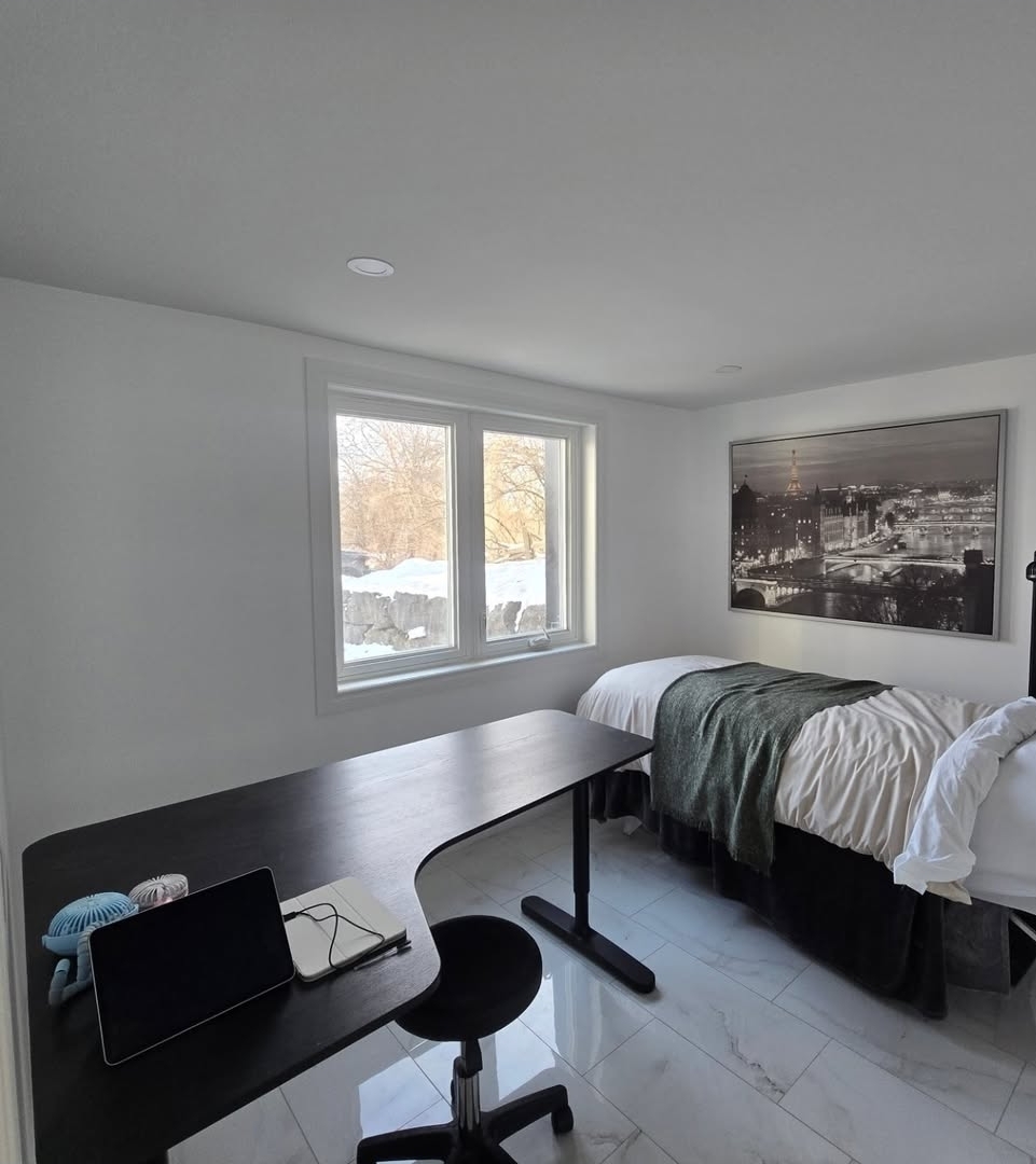 Finished basement bedroom and office space with new window, dark wood desk and hardwood flooring