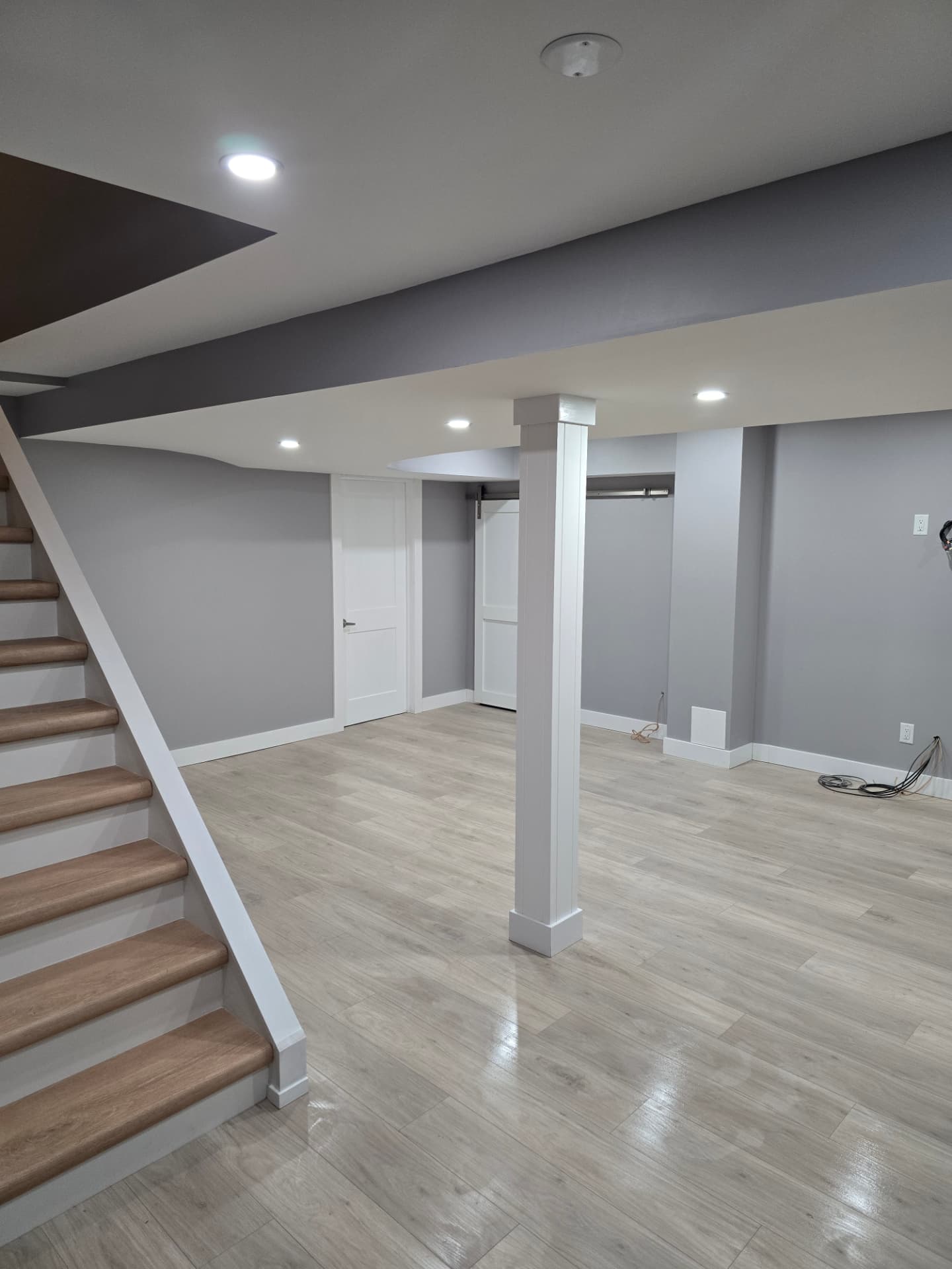 Finished basement rec room with support column wrap, stairs and new doors
