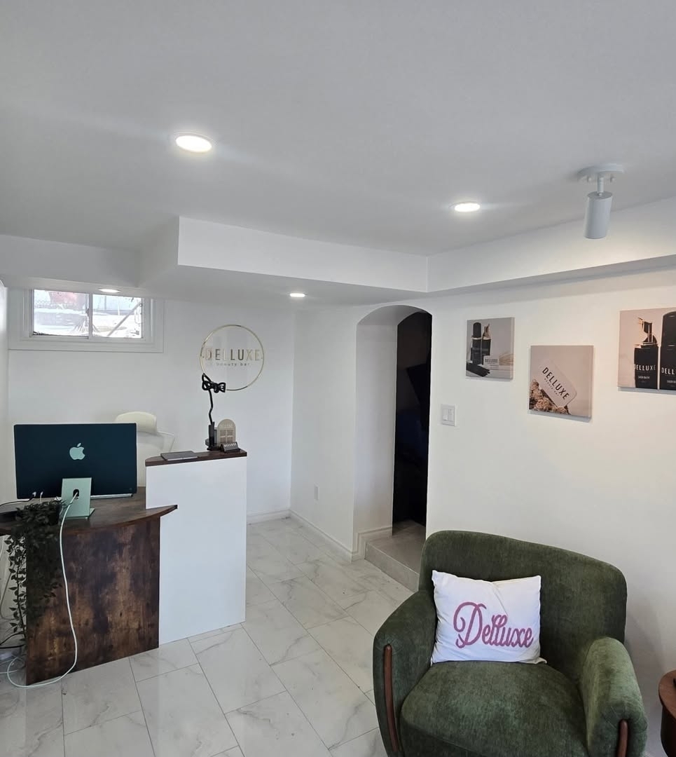 Bright basement reception area with custom wood desk, green lounge chair and pot lights