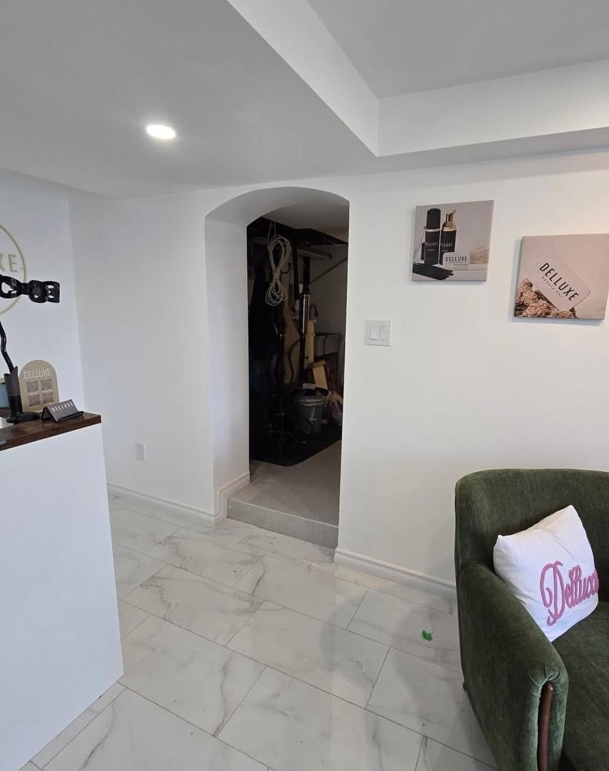 Basement reception area with arched doorway, marble-look tile flooring and custom wood desk detail