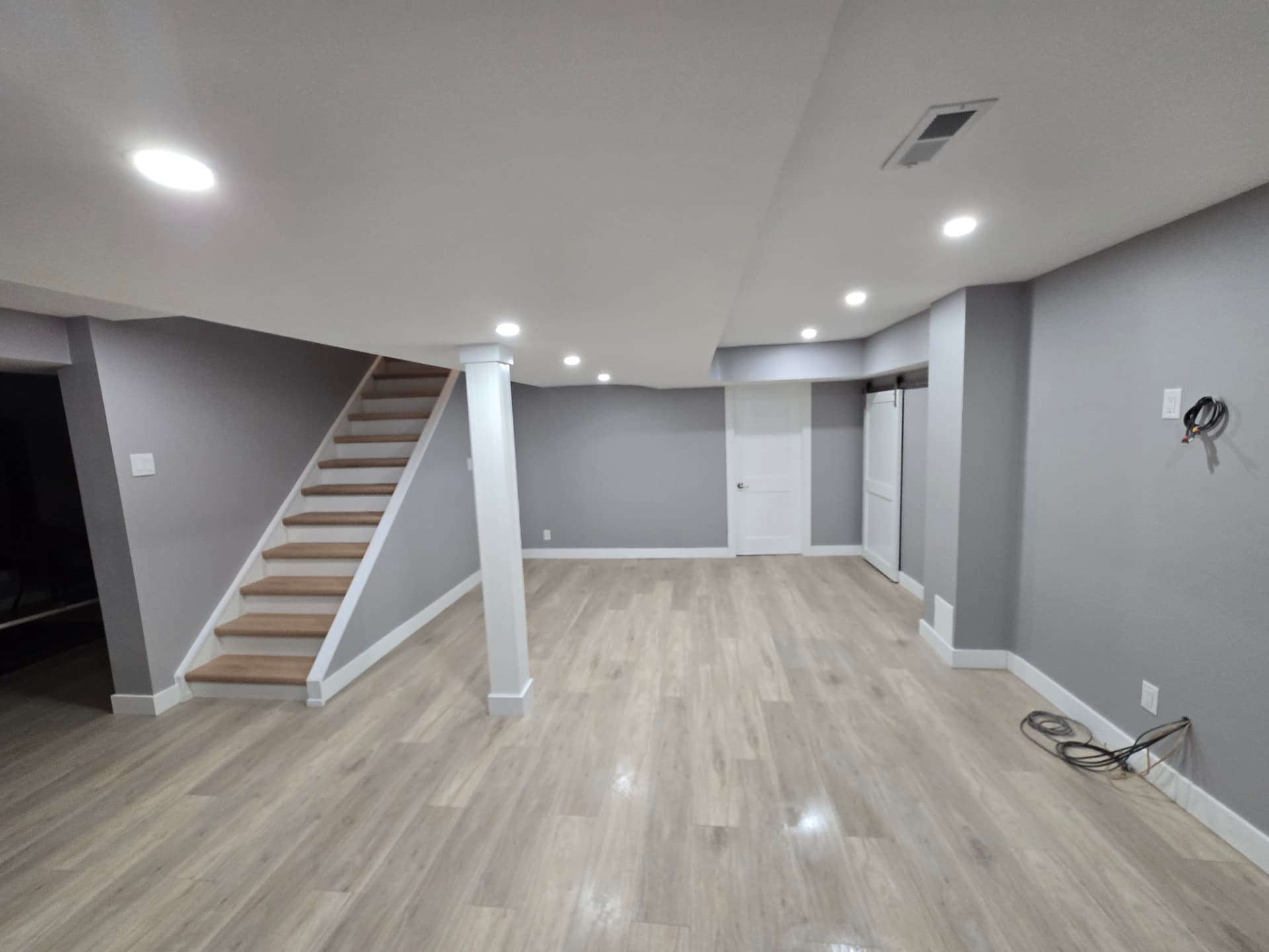 Finished basement with open staircase, sliding barn door and recessed lighting