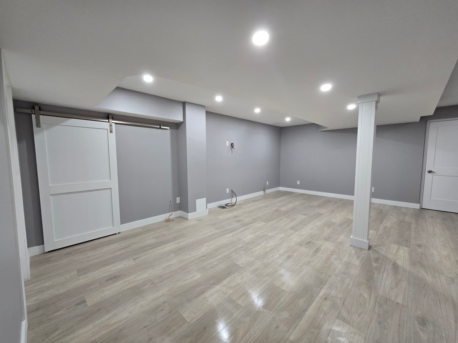Finished basement with sliding barn door closet and recessed lighting